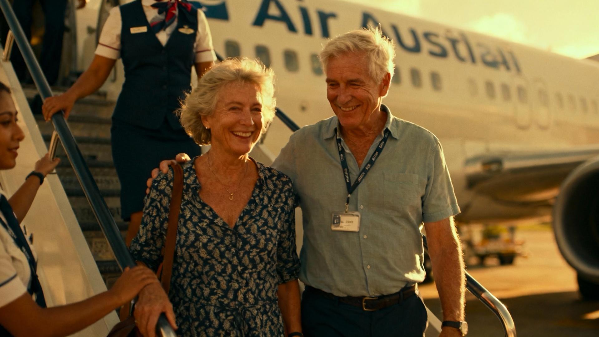 Couple âgé souriant montant dans un avion Air Austral avec l'aide d'un membre de l'équipage