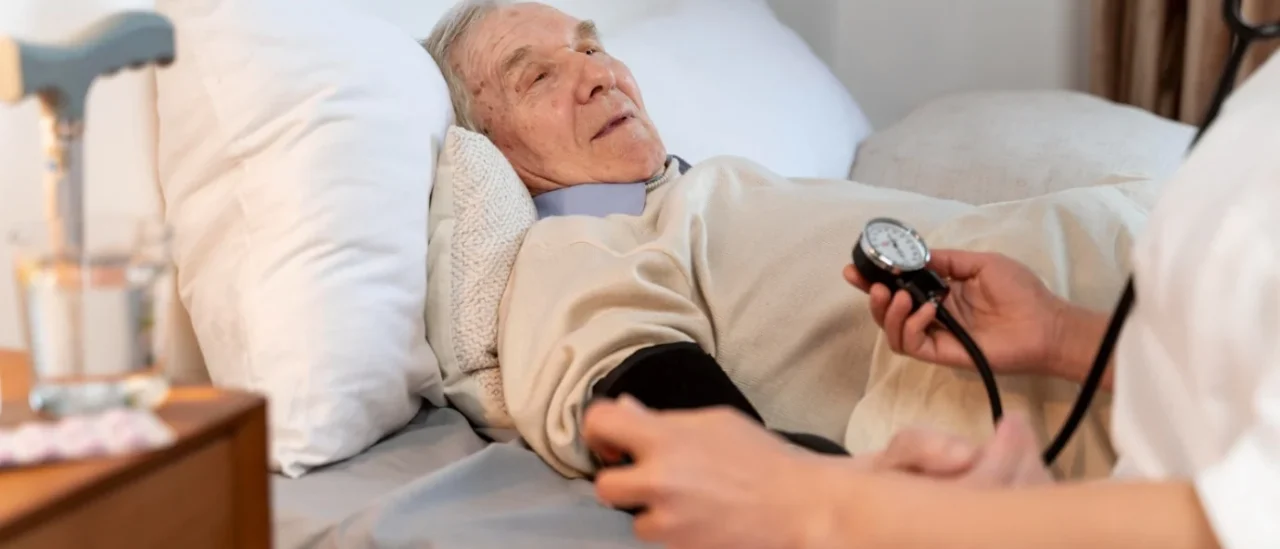 Professionnel de santé mesurant la tension d’un senior à domicile