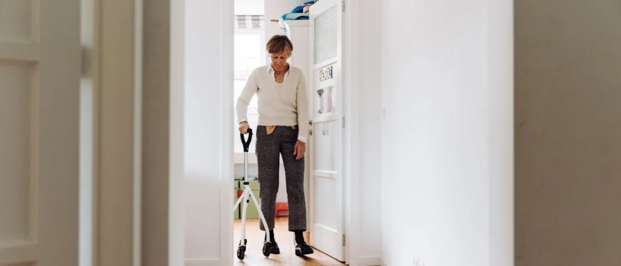 Senior se déplaçant avec une aide à la marche dans un couloir dégagé